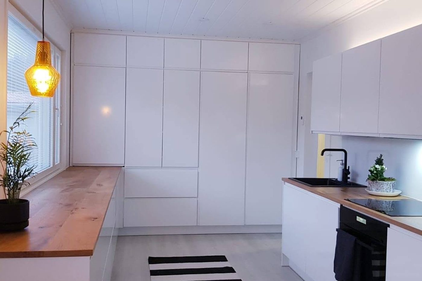 Valmis keittiö vaaleilla kalusteilla ja puisella tasolla