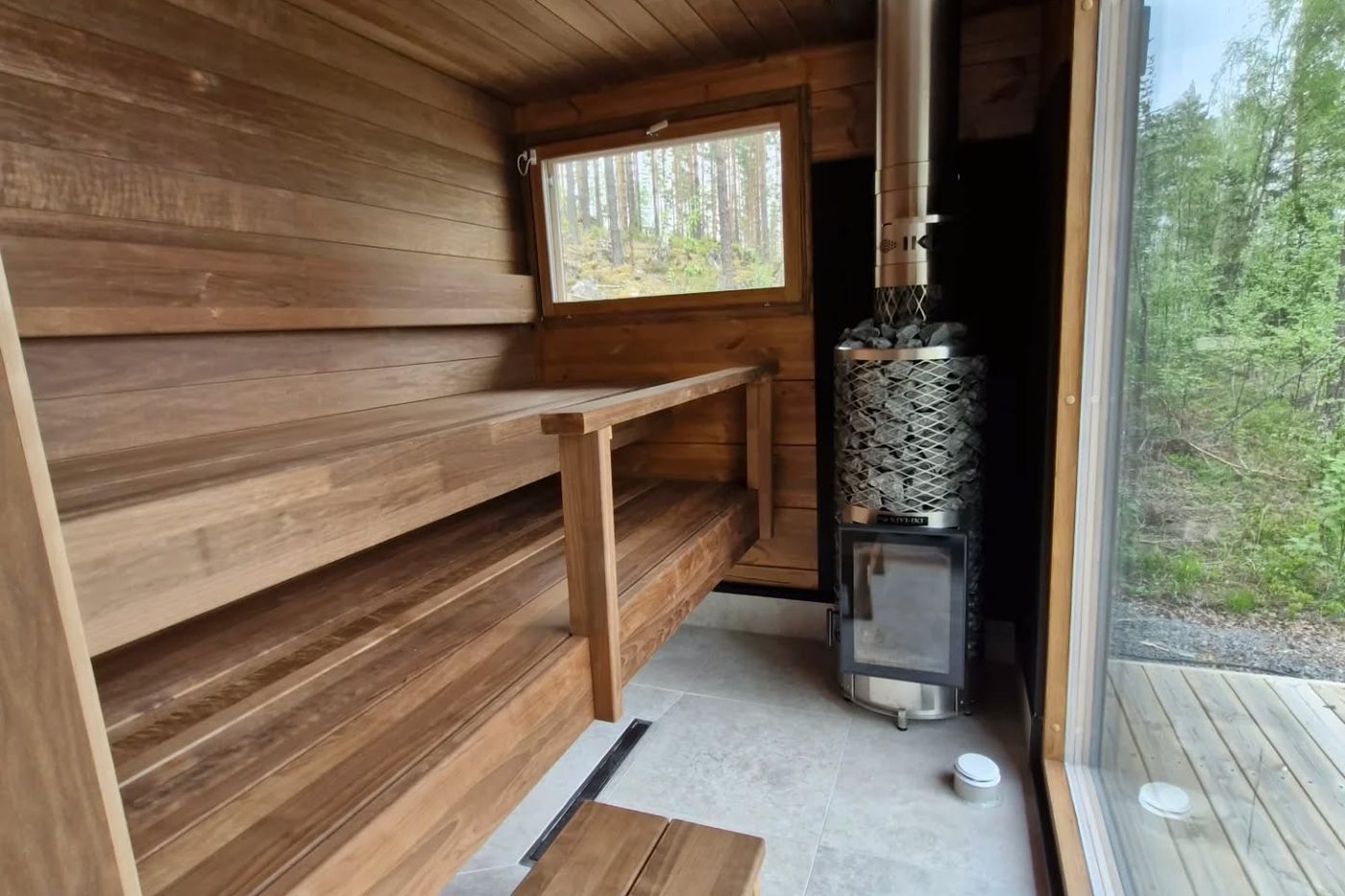 Puulauteinen sauna ja kiuas ikkunan äärellä