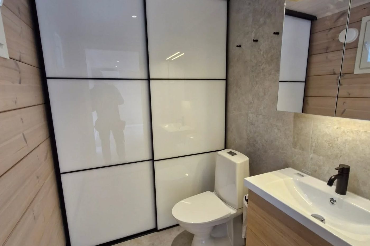 Pesuhuone lasiseinällä, wc-istuimella ja allaskalusteella